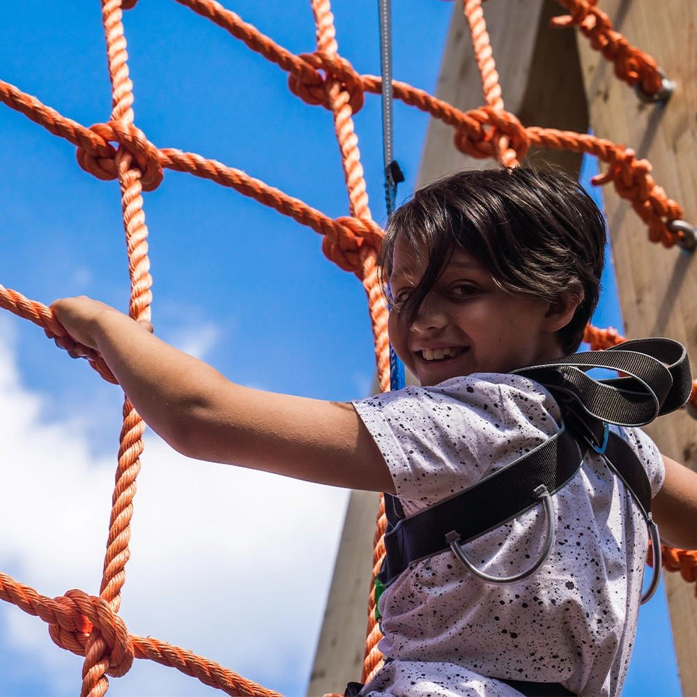 Kid smiling on the climbing wall at hangloose adventure