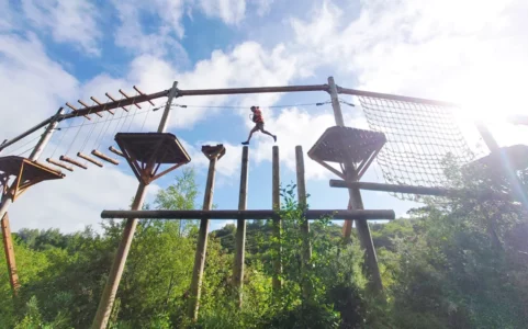 A guy jumping across the treetop obstacle course